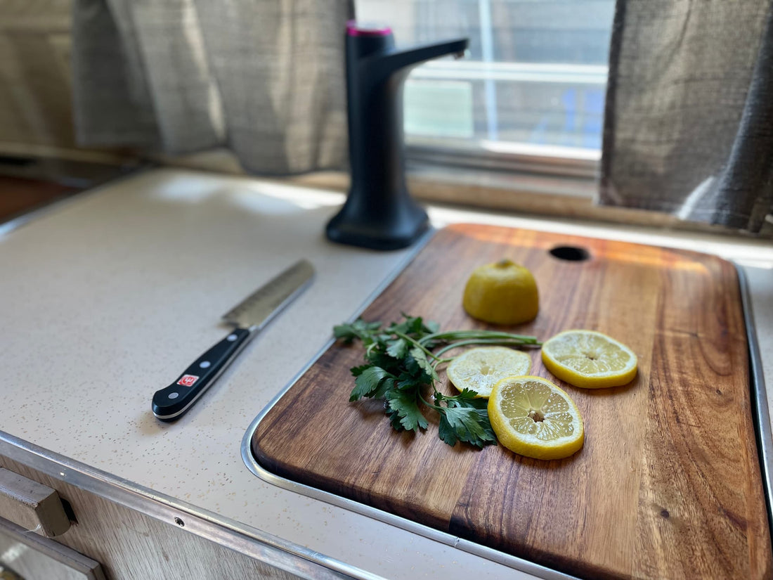 Acacia cutting board in use in the 1964 Ideal canned ham camper -- lemon and herbs on the custom-fitted sink cover