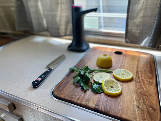 Acacia cutting board in use in the 1964 Ideal canned ham camper -- lemon and herbs on the custom-fitted sink cover