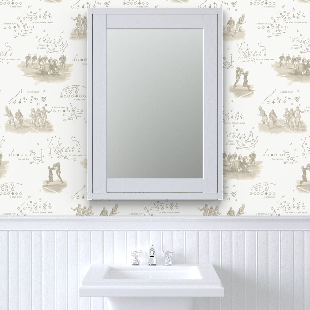 Antique sepia football wallpaper above white beadboard in a classic bathroom with pedestal sink — vintage americana wallpaper for powder rooms