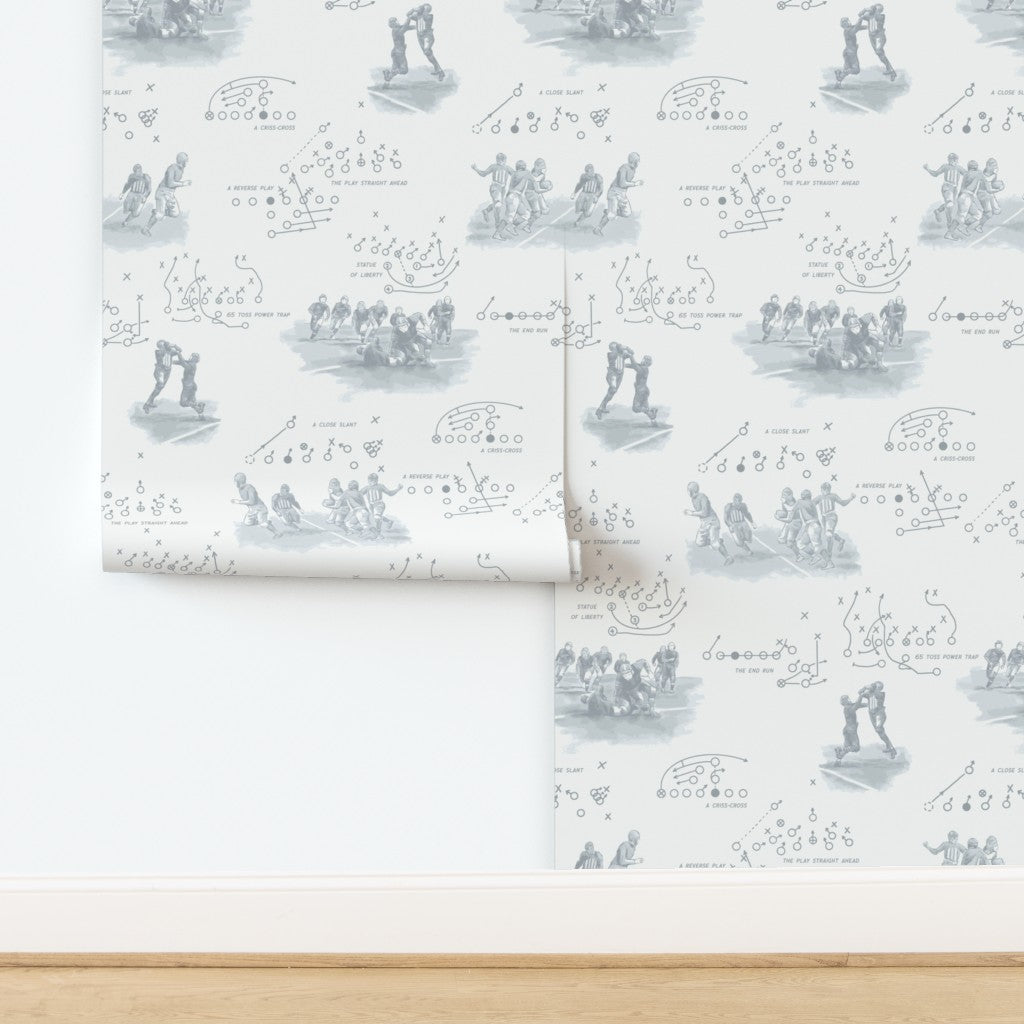 Vintage football wallpaper in pewter gray featuring hand-illustrated 1920s players and period play diagrams on warm off-white