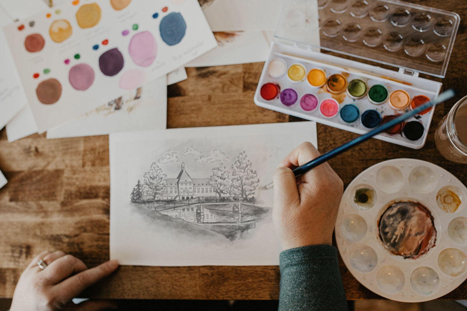 Architectural illustrator Stacie Humpherys drawing a hand-rendered ink illustration of a historic college building — Pine + Feather Studio custom commission process