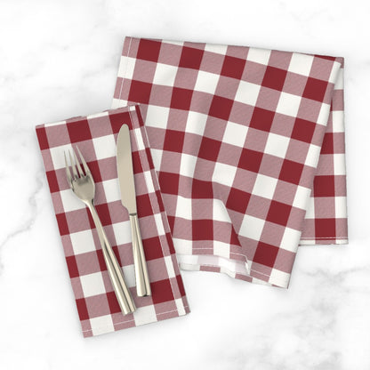 Red buffalo check dinner napkin with a knife and fork on a white marble tabletop