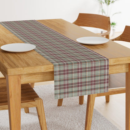 Cranberry and sage plaid table runner down the center of a wood dining table with two white plates