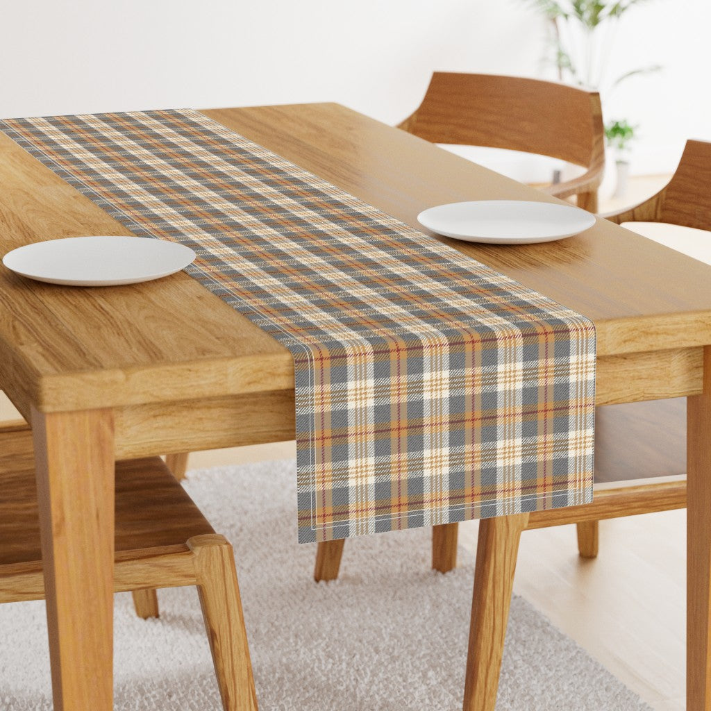 Charcoal and gold plaid table runner down the center of a wood dining table with two white plates