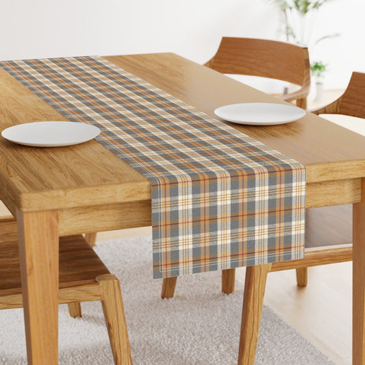 Charcoal and gold plaid table runner down the center of a wood dining table with two white plates