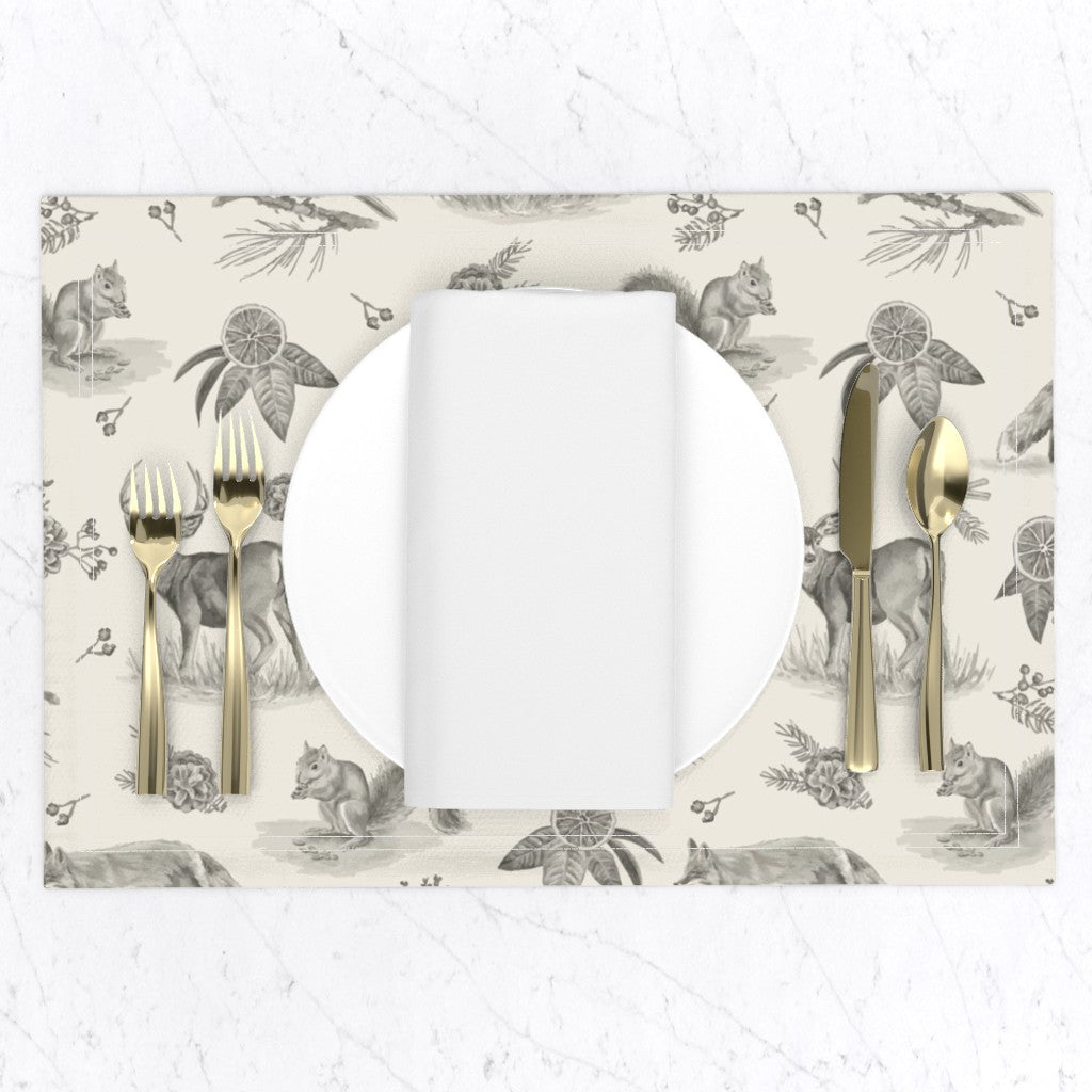 Charcoal woodland toile placemat set with a white plate, napkin and gold flatware on a marble table