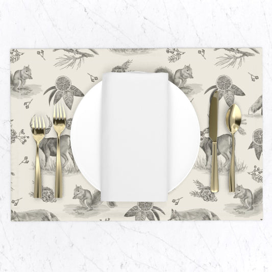 Charcoal woodland toile placemat set with a white plate, napkin and gold flatware on a marble table