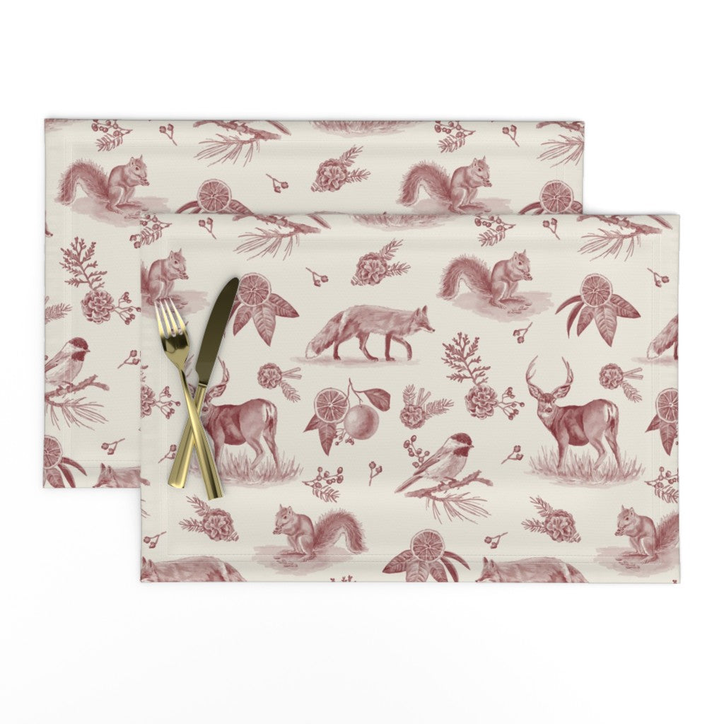 Set of two Woodland Toile placemats in Cranberry with a knife and fork, showing deer, fox and chickadees