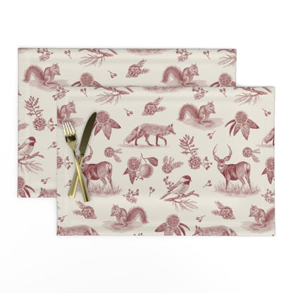 Set of two Woodland Toile placemats in Cranberry with a knife and fork, showing deer, fox and chickadees