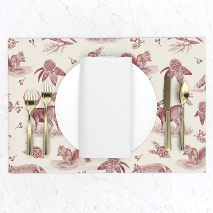 Cranberry woodland toile placemat set with a white plate, napkin and gold flatware on a marble table
