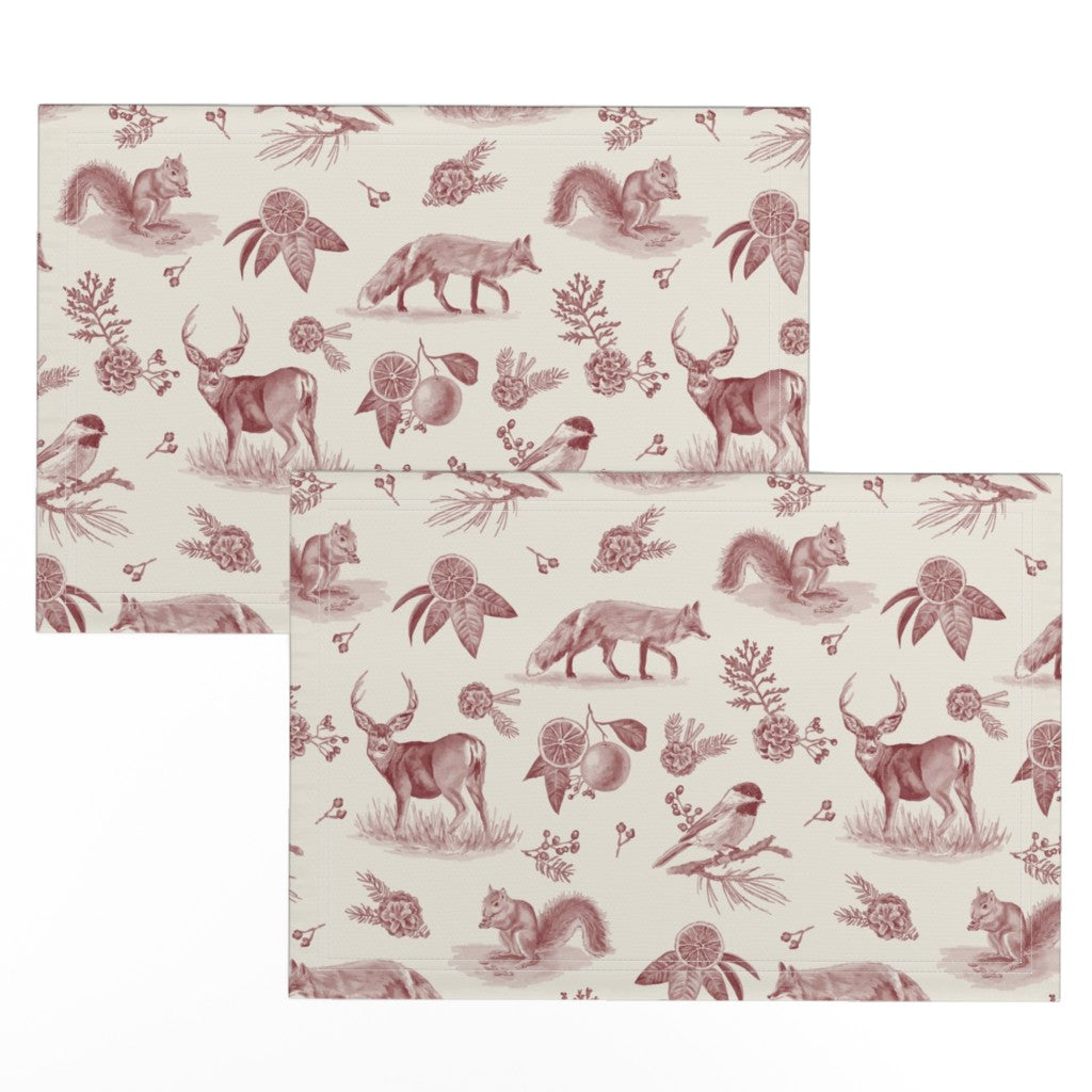 Two cranberry toile placemats offset to show the hand-drawn deer, fox and squirrel